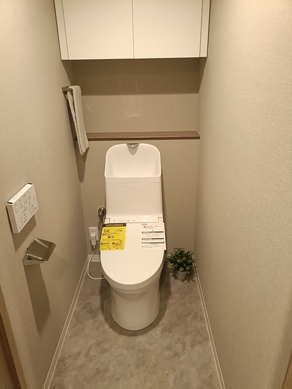 温水洗浄便座付きの快適なトイレ空間。上部収納棚とカウンターを備え、小物もすっきりと収まります。 日興千里丘スカイマンションB棟 406号室 その他